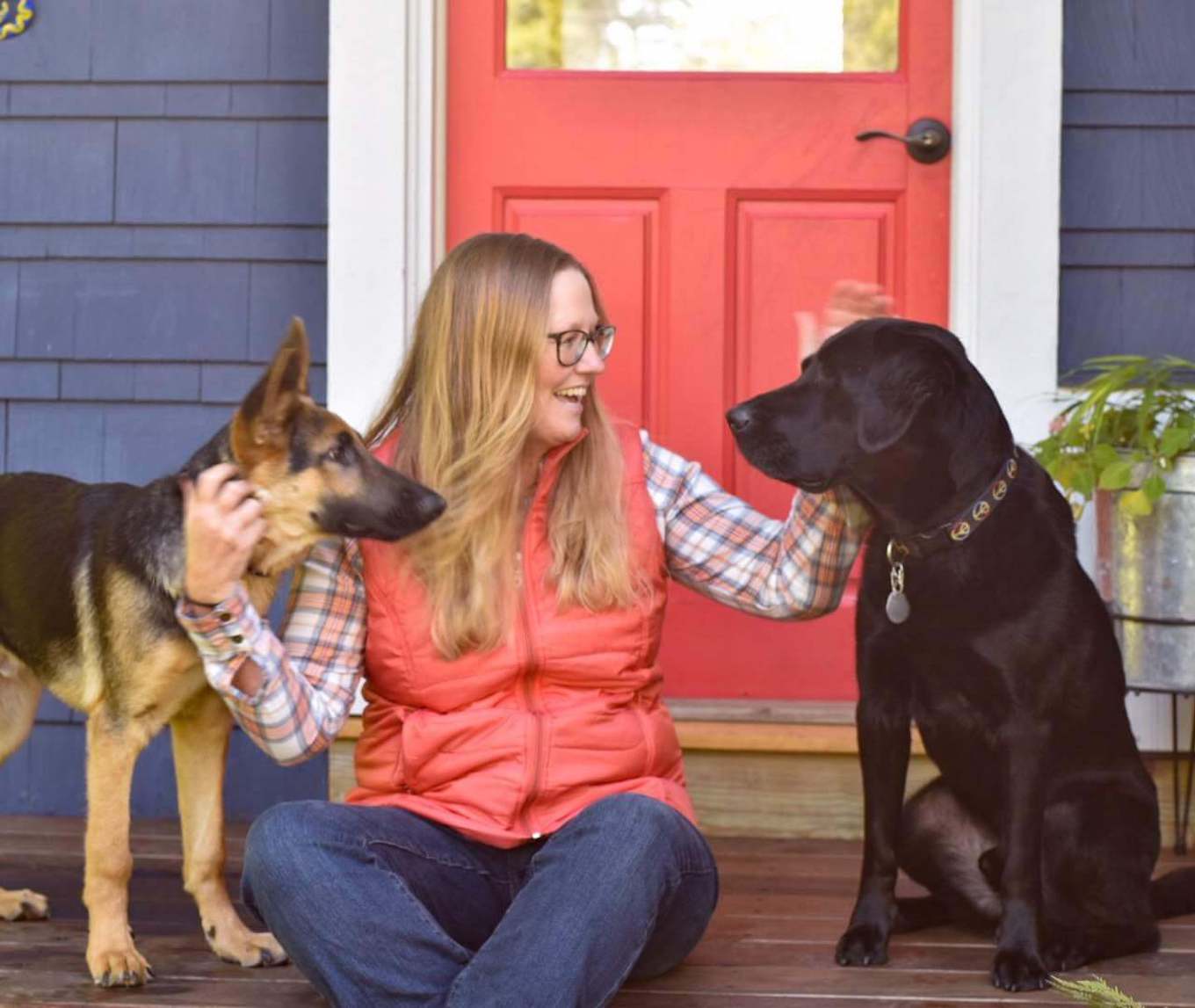 A pet portrait featuring a woman sitting with a dog on each side.