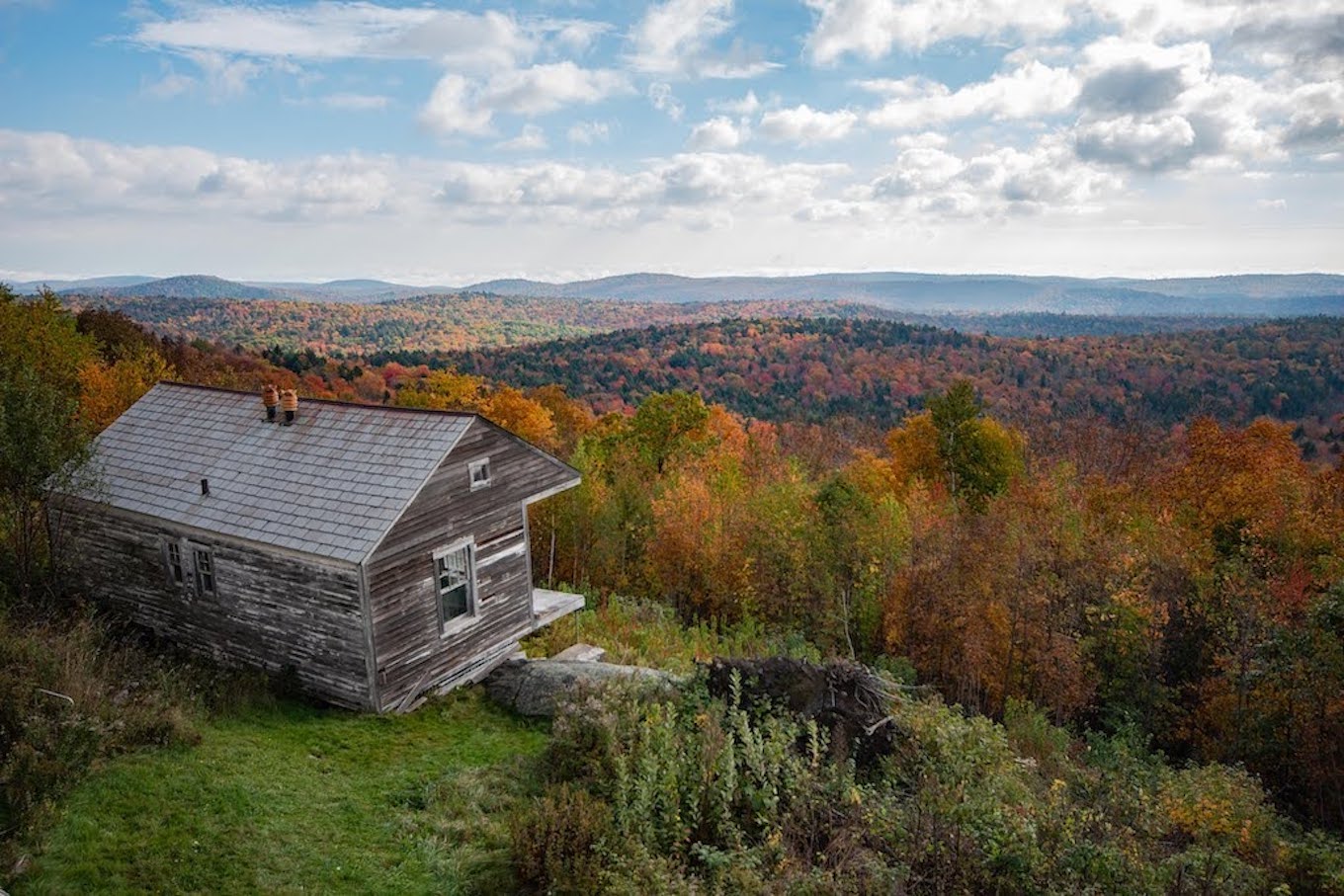 An old building on the edge of the woods during the fall.