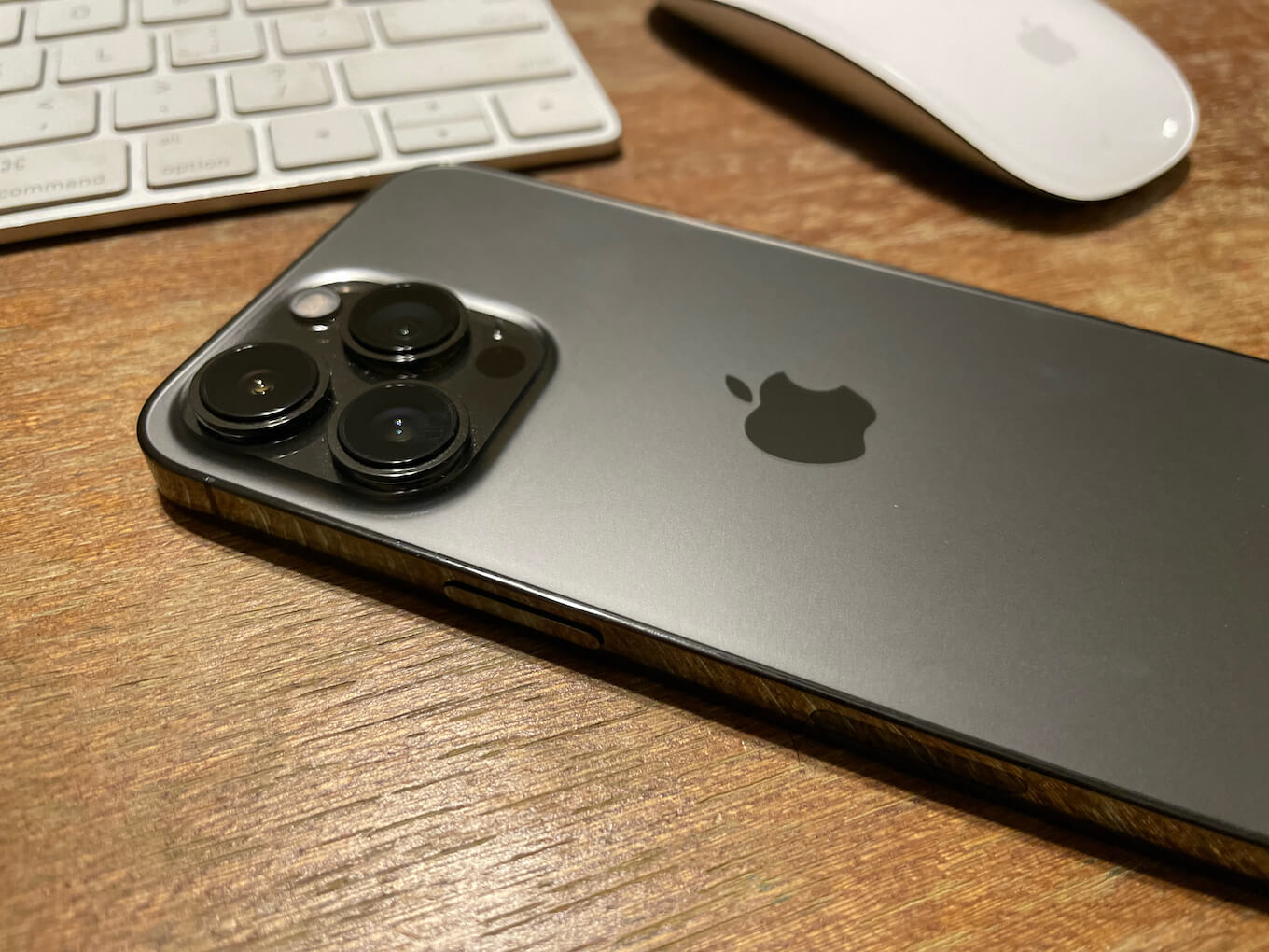 Graphite iPhone 13 Pro on a table next to a keyboard and a mouse